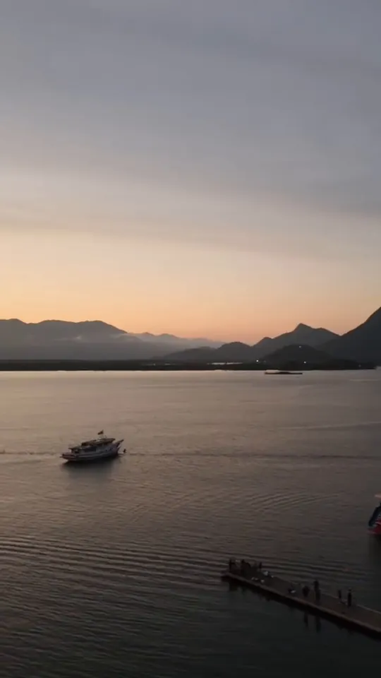 Embarcações na baía com montanhas no horizonte